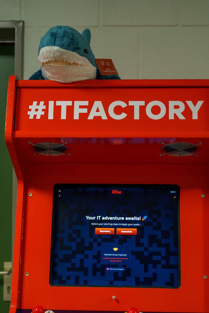 Bright arcade machine at IT Factory, topped with a plush toy shark, inviting IT adventures.